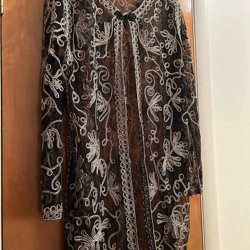 Black and gold jacket with circle collar. One button at neck line .